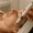 Close-up of a woman lying down with eyes closed while receiving a relaxing facial treatment using a modern skincare device.